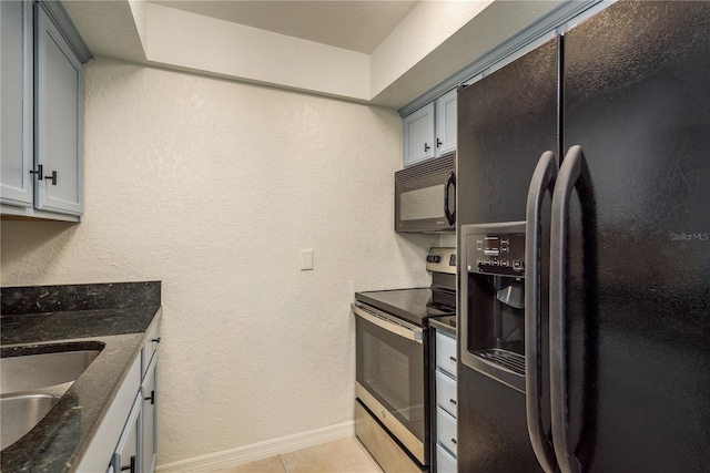 720 Lyndhurst St Unit 1121, Dunedin, FL 34698 - kitchen with black appliances, a sink, baseboards, dark stone counters, and light tile patterned floors