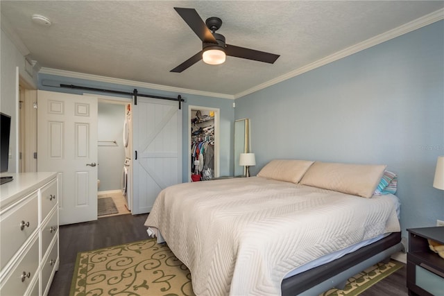 720 Lyndhurst St Unit 1121, Dunedin, FL 34698 - bedroom featuring dark wood-style flooring, ornamental molding, a barn door, a closet, and a spacious closet