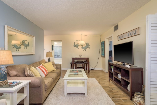 living room featuring baseboards, visible vents, wood finished floors, and a textured ceiling