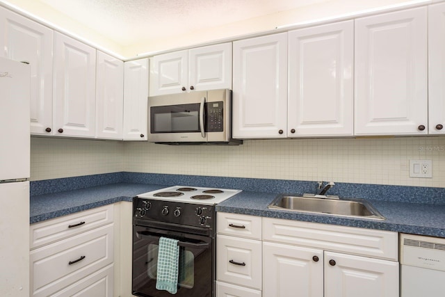 kitchen with white appliances, dark countertops, white cabinets, and a sink