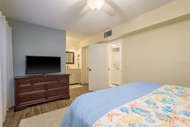 bedroom with visible vents, a textured ceiling, ensuite bathroom, and wood tiled floor