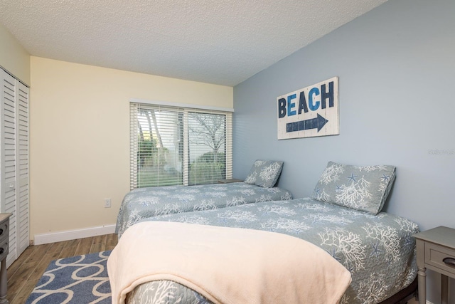 bedroom featuring baseboards, a textured ceiling, wood finished floors, and a closet