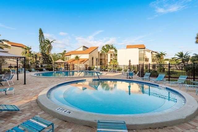 pool featuring a residential view, a gazebo, fence, and a patio area