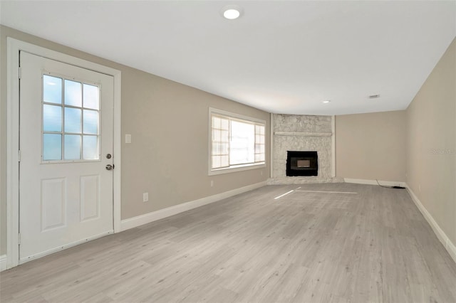 7323 Andre Dr, Zephyrhills, FL 33541 - unfurnished living room featuring baseboards, light wood-style flooring, recessed lighting, and a stone fireplace