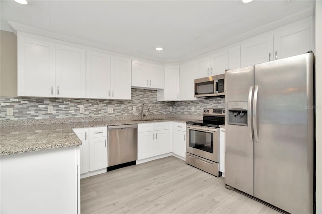 7323 Andre Dr, Zephyrhills, FL 33541 - kitchen with light wood-type flooring, a sink, stainless steel appliances, and decorative backsplash