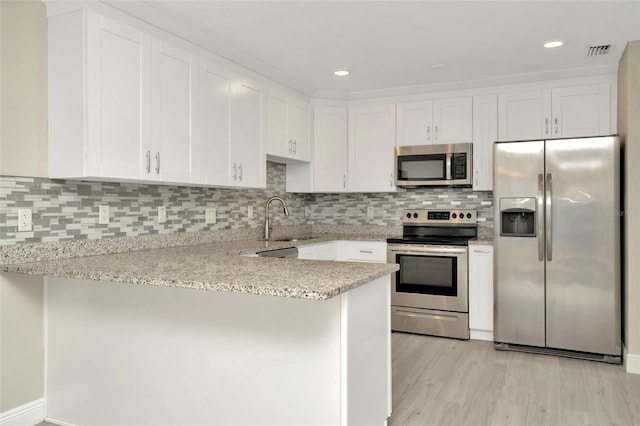 7323 Andre Dr, Zephyrhills, FL 33541 - kitchen featuring stainless steel appliances, a sink, visible vents, white cabinets, and a peninsula