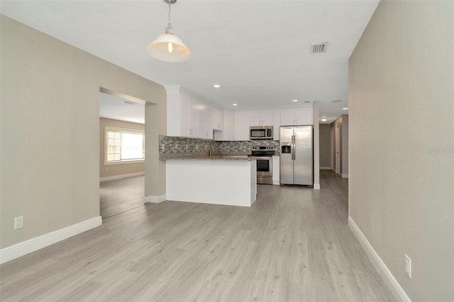 7323 Andre Dr, Zephyrhills, FL 33541 - kitchen featuring baseboards, stainless steel appliances, white cabinetry, light wood-type flooring, and backsplash