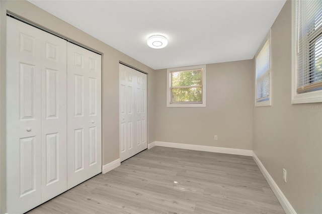 7323 Andre Dr, Zephyrhills, FL 33541 - unfurnished bedroom featuring baseboards, light wood-style floors, and two closets