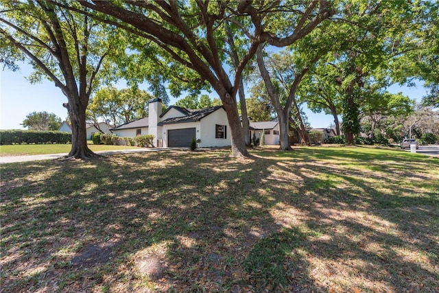 2715 Willow Oaks Dr, Valrico, FL 33594 - view of front of house with a chimney, a garage, stucco siding, and a front lawn