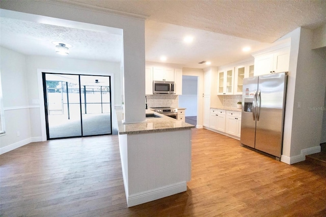 2715 Willow Oaks Dr, Valrico, FL 33594 - kitchen with stainless steel appliances, decorative backsplash, a textured ceiling, light wood finished floors, and glass insert cabinets