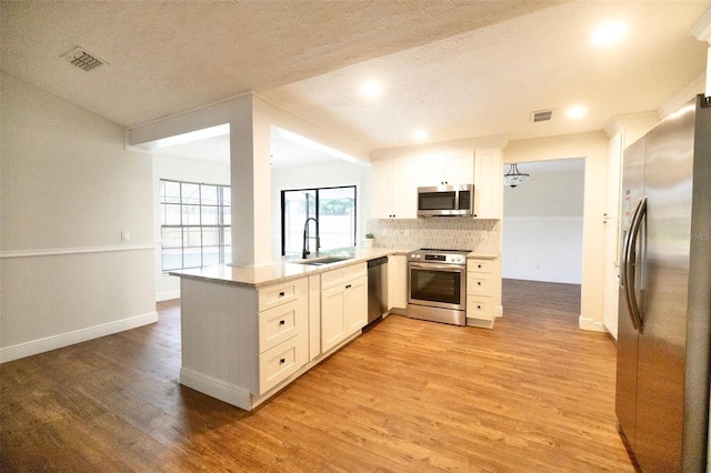 2715 Willow Oaks Dr, Valrico, FL 33594 - kitchen featuring stainless steel appliances, a sink, a peninsula, light wood-style floors, and white cabinets