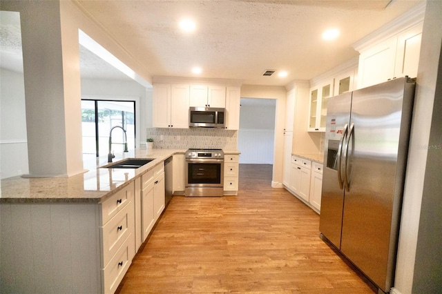 2715 Willow Oaks Dr, Valrico, FL 33594 - kitchen featuring stainless steel appliances, a sink, light wood-style flooring, decorative backsplash, and light stone counters