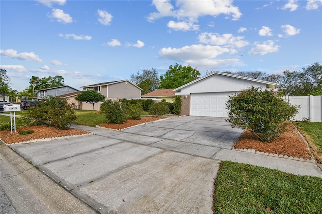 ranch-style home with concrete driveway, an attached garage, and fence