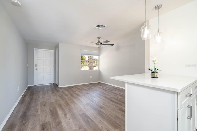 interior space with baseboards, wood finished floors, visible vents, and ceiling fan