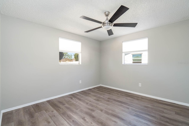 empty room with a textured ceiling, a ceiling fan, baseboards, and wood finished floors