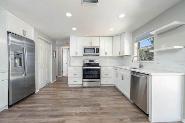 kitchen featuring light wood finished floors, visible vents, decorative backsplash, stainless steel appliances, and a sink