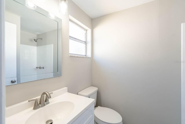 bathroom featuring vanity, toilet, and walk in shower