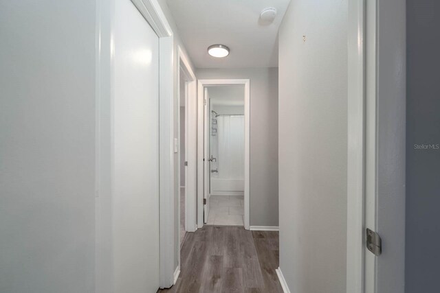 corridor with wood finished floors and baseboards