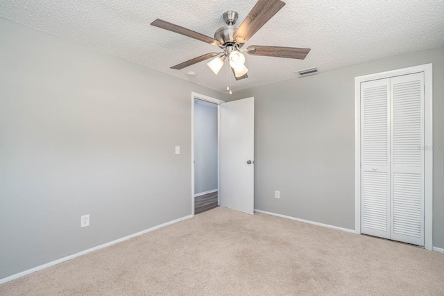 unfurnished bedroom with visible vents, light carpet, a textured ceiling, a closet, and baseboards