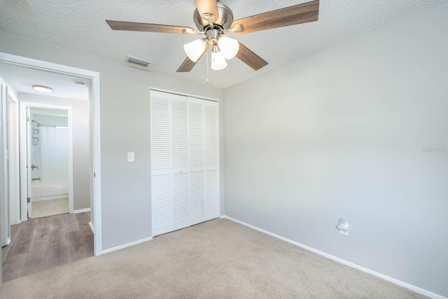 unfurnished bedroom featuring visible vents, carpet, a closet, and a textured ceiling