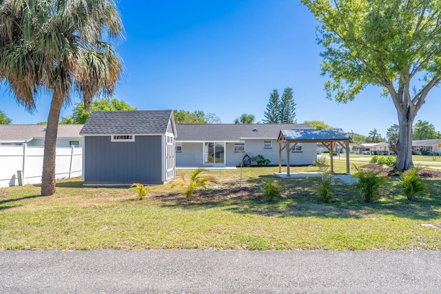 ranch-style house with an outbuilding, a front lawn, fence, a storage shed, and a detached carport