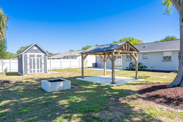 view of yard featuring a gazebo, a fenced backyard, a storage shed, and an outdoor structure