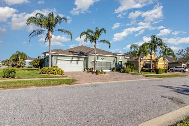 ranch-style house featuring a front yard, decorative driveway, a garage, and stucco siding