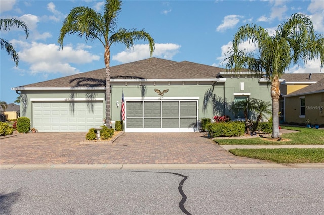 single story home with a garage, decorative driveway, and stucco siding