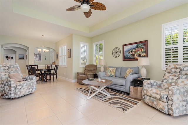 689 Chipper Dr, Sun City Center, FL 33573 - tiled living area with a tray ceiling, ceiling fan with notable chandelier, baseboards, and arched walkways