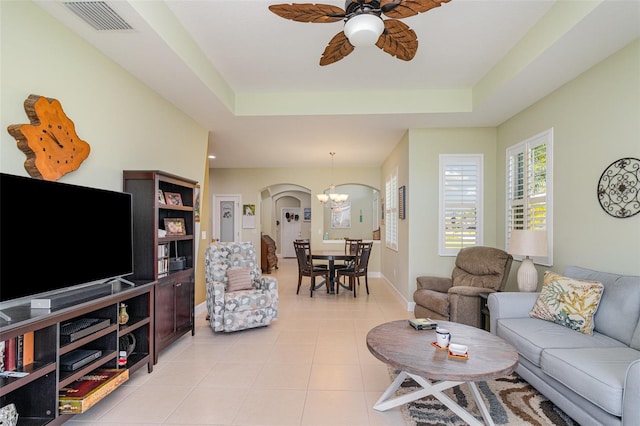 689 Chipper Dr, Sun City Center, FL 33573 - living area featuring visible vents, light tile patterned flooring, arched walkways, a raised ceiling, and ceiling fan with notable chandelier