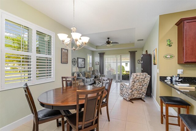 689 Chipper Dr, Sun City Center, FL 33573 - dining space featuring light tile patterned floors, visible vents, ceiling fan with notable chandelier, and a tray ceiling
