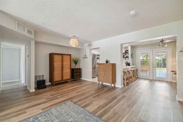 living room featuring visible vents, french doors, baseboards, and wood finished floors