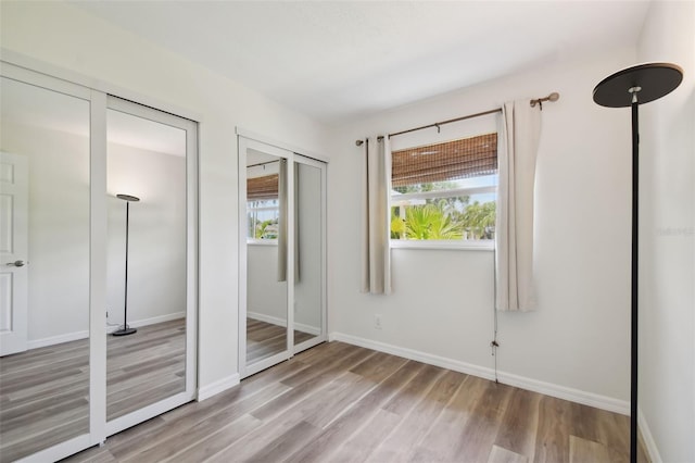 unfurnished bedroom with baseboards, multiple closets, and wood finished floors