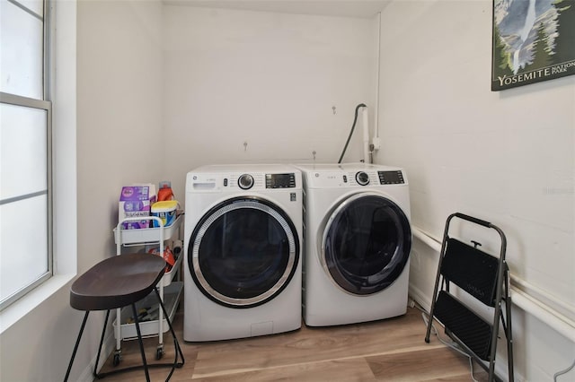 clothes washing area featuring laundry area, wood finished floors, and washing machine and dryer