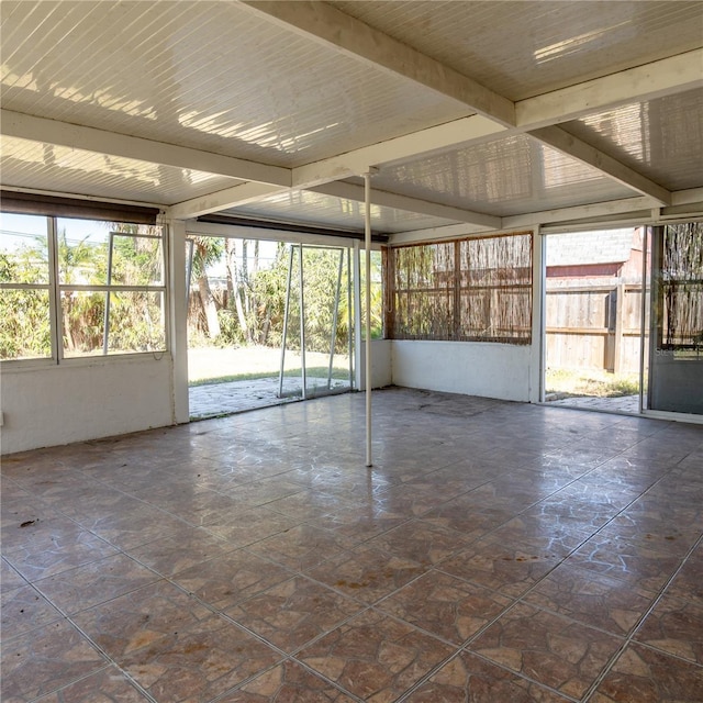 unfurnished sunroom featuring a wealth of natural light and beamed ceiling