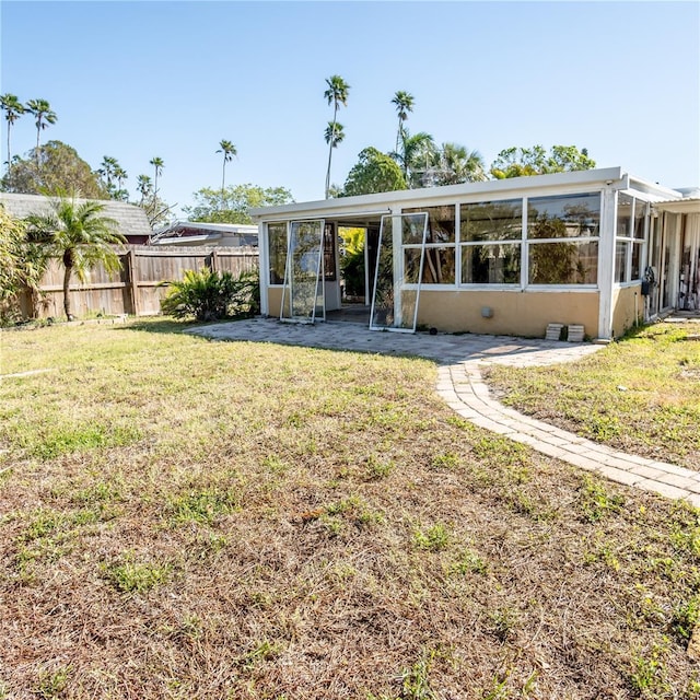 rear view of property with fence, a lawn, and a sunroom
