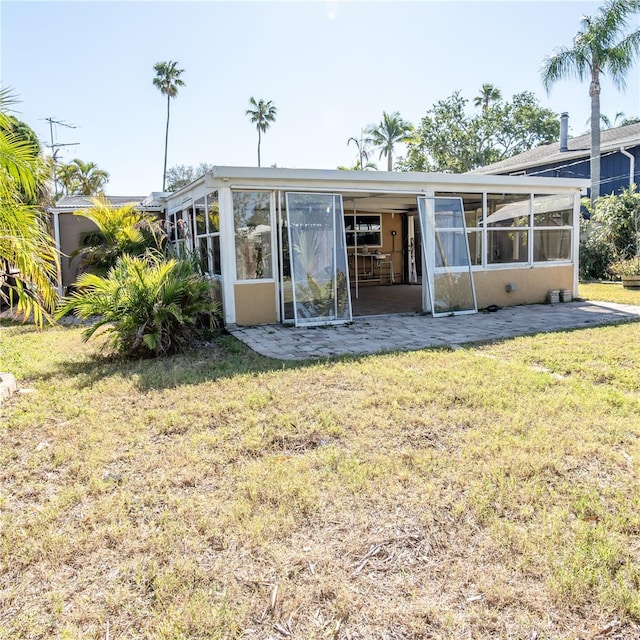 back of property with a lawn and a sunroom