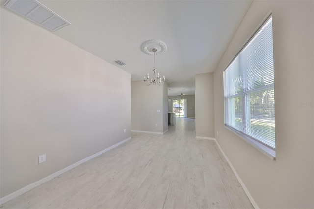 interior space featuring visible vents, baseboards, a notable chandelier, and light wood-style flooring