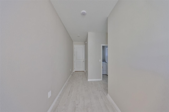 corridor featuring light wood-style flooring and baseboards