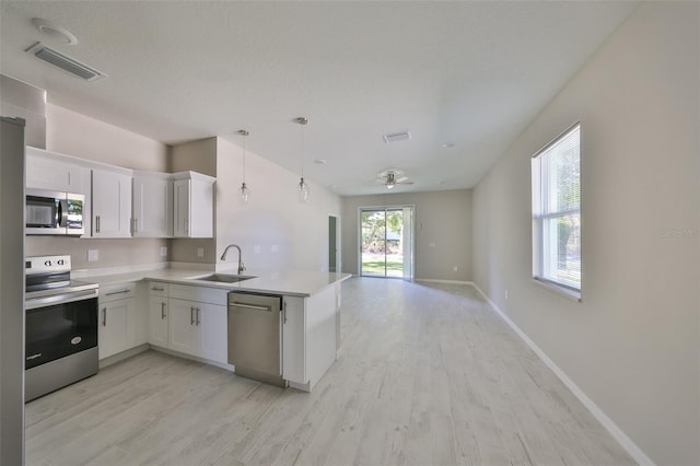 kitchen featuring visible vents, a sink, white cabinets, appliances with stainless steel finishes, and open floor plan