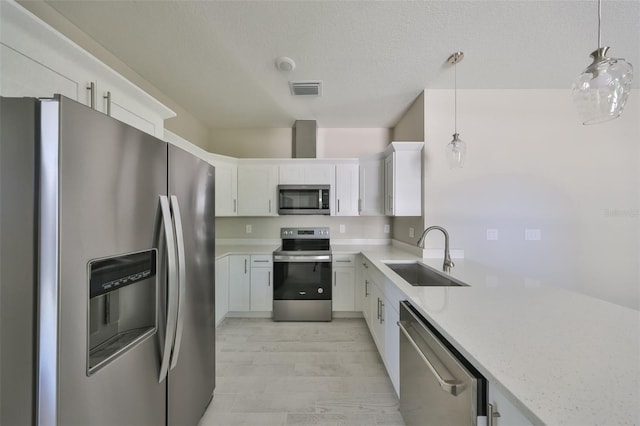 kitchen with visible vents, a sink, appliances with stainless steel finishes, pendant lighting, and white cabinetry