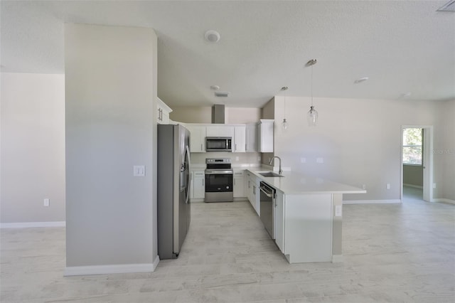 kitchen featuring a peninsula, a sink, stainless steel appliances, light countertops, and white cabinets
