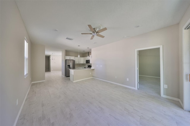 unfurnished living room featuring visible vents, baseboards, light wood-style floors, and ceiling fan