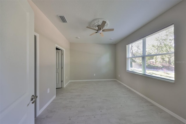 spare room featuring visible vents, a textured ceiling, baseboards, and a ceiling fan