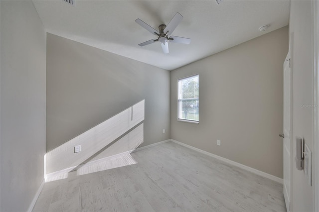 unfurnished room with baseboards, a ceiling fan, and light wood finished floors