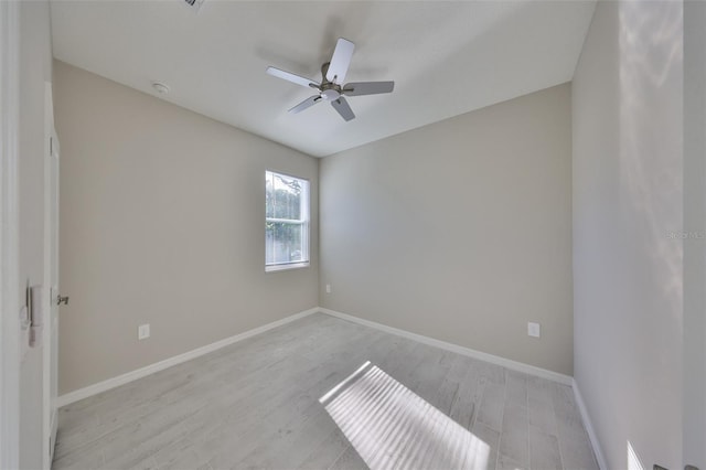 empty room featuring a ceiling fan, baseboards, and light wood-type flooring
