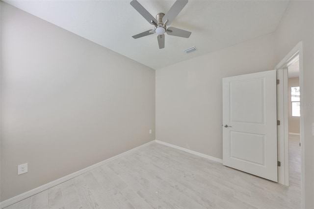 empty room with a ceiling fan, visible vents, light wood-style floors, and baseboards
