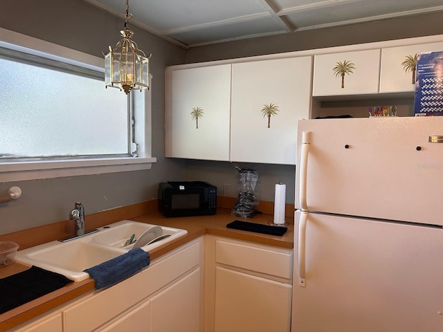 5562 S US-301, Bushnell, FL 33513 - kitchen with an inviting chandelier, freestanding refrigerator, a sink, black microwave, and white cabinetry