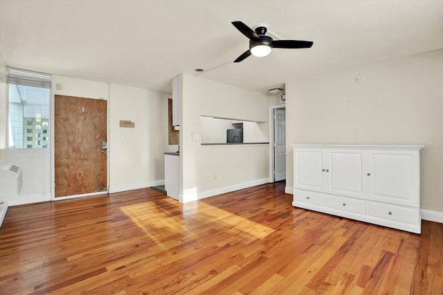 1301 S Howard Ave Unit B24, Tampa, FL 33606 - unfurnished living room featuring an AC wall unit, baseboards, a ceiling fan, and light wood-style flooring