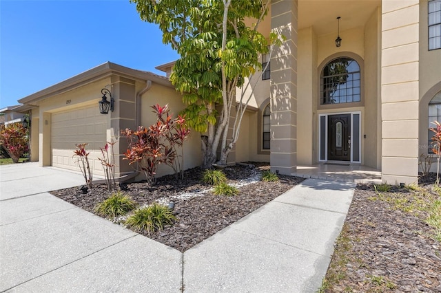 property entrance with stucco siding, driveway, and a garage